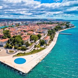Zadar, Croacia - Vista panorámica aérea del casco antiguo de Zadar junto al mar Adriático con el monumento El Saludo al Sol, el horizonte de Zadar, el órgano del mar, el cielo azul y el dorado sol naciente en una mañana de verano.